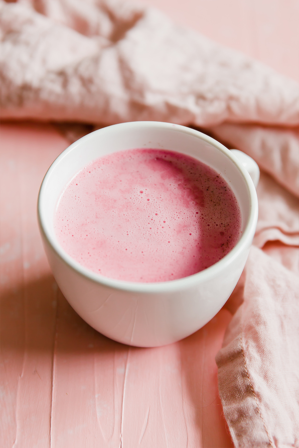 Pink beet latte in a white mug.