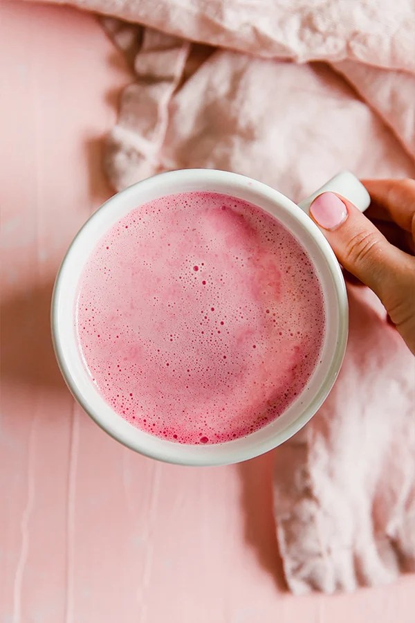 Person holding a mug of pink beet latte.