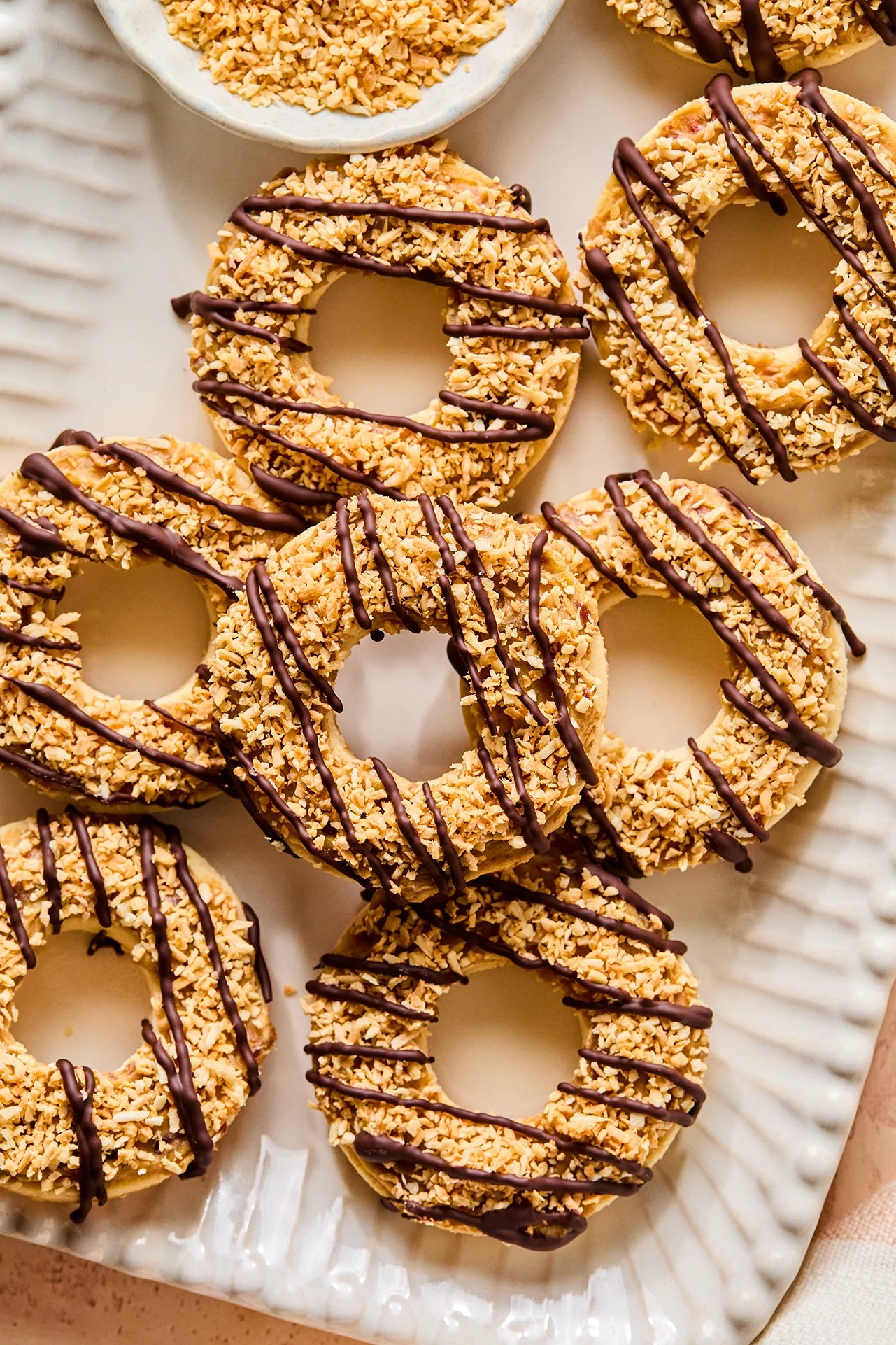Samoa cookies on a platter with shredded coconut in a bowl on the side.
