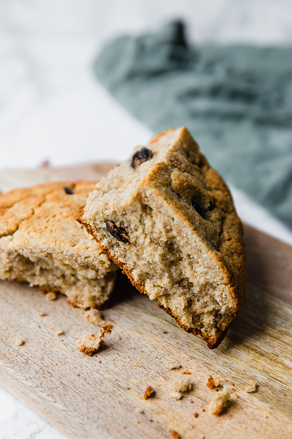 A wooden cutting board with two pieces of Irish soda bread on it.