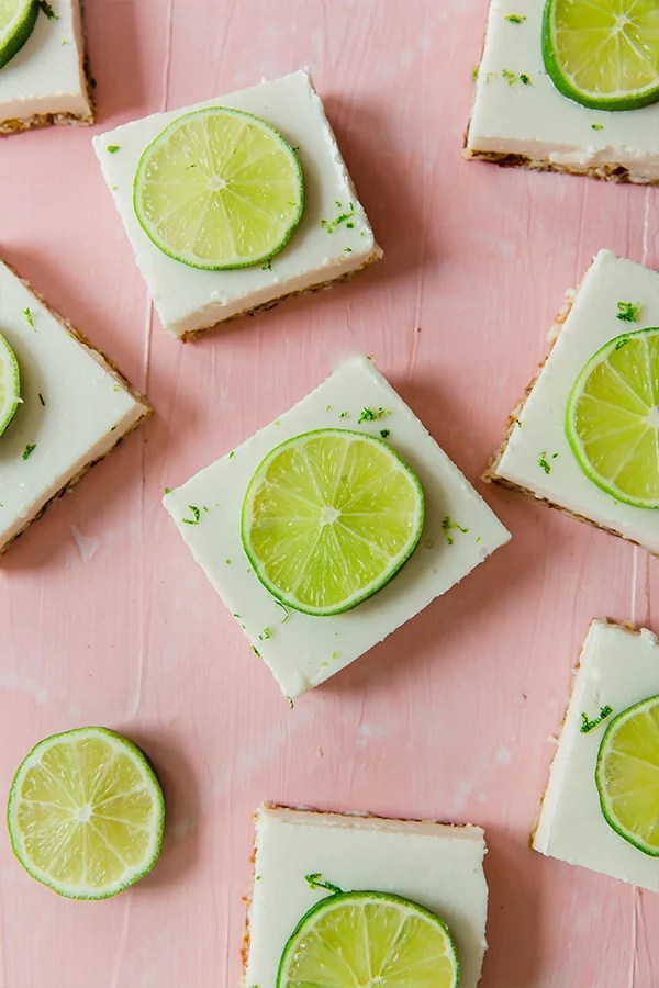 A pink background with key lime squares topped with fresh key limes ready to be enjoyed.