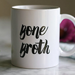 A white mug with text on it saying Bone Broth.