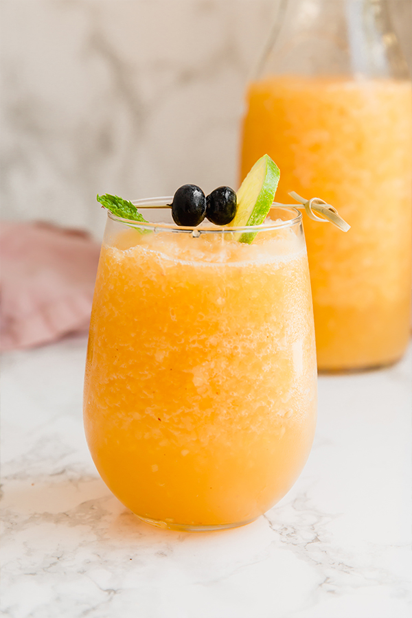 Two glasses filled with frozen peach bellini mocktail