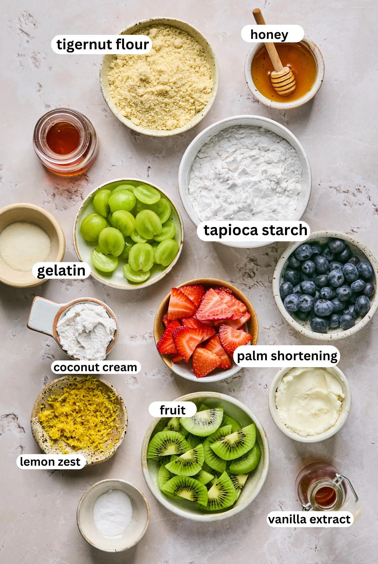 Sugar cookie fruit pizza ingredients in seperate bowls.