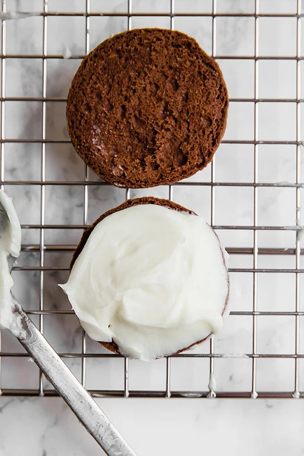 The open-face sandwich cookie being iced.
