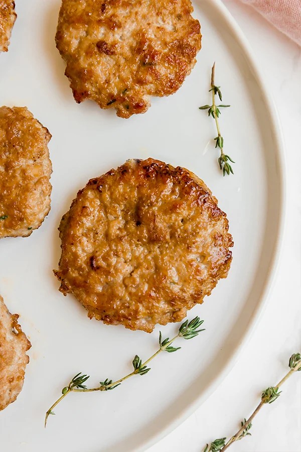 A white plate with homemade sausage patties on it.