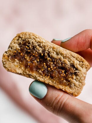 A hand holding a homemade gluten free fig newton in it.