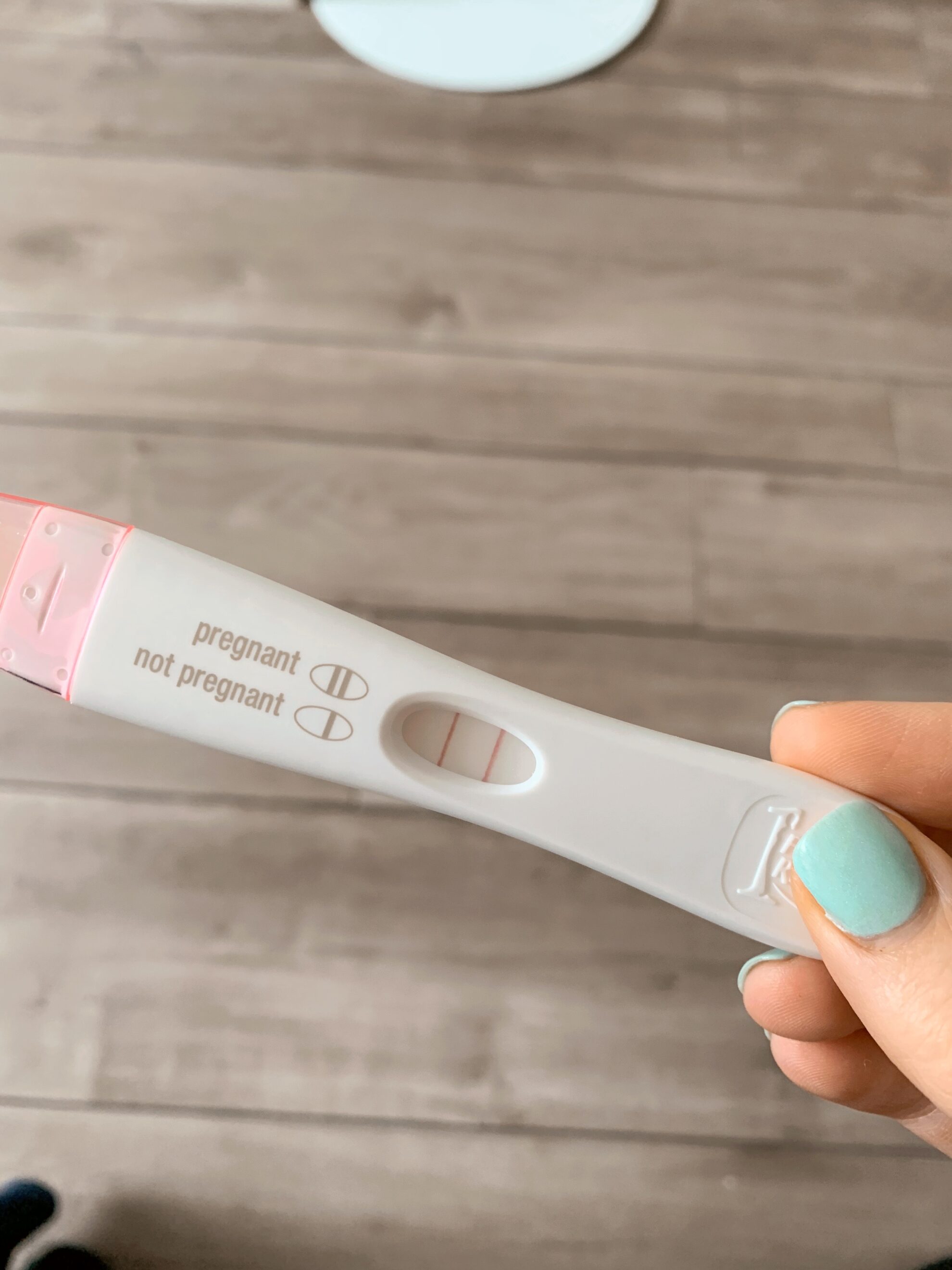 A hand holding a pregnancy test with two lines on it indicating it is positive.