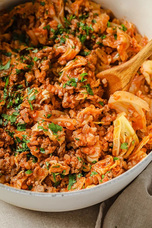 Wooden spoon in a pan of unstuffed cabbage roll.