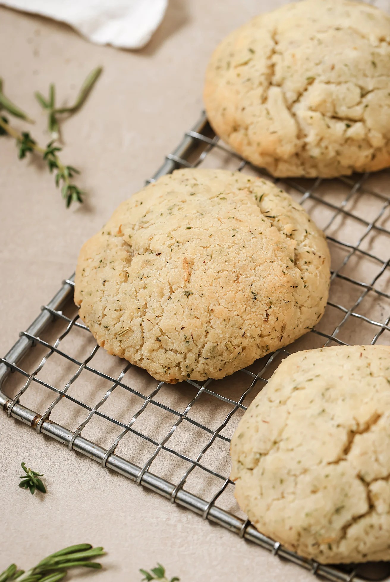 Garlic and herb dinner rolls on a wire rack with thyme in the background.