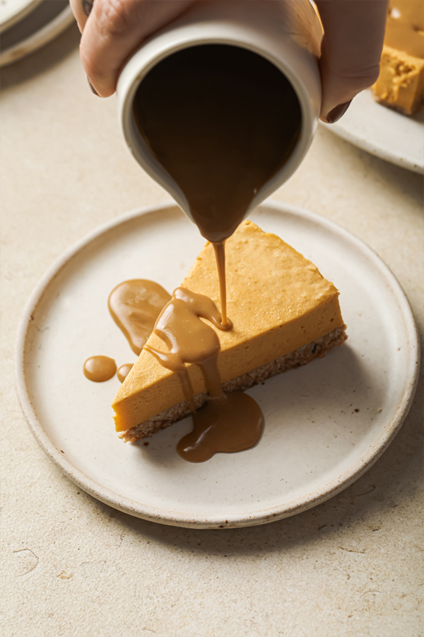 Caramel pouring over a slice of pumpkin cheesecake.