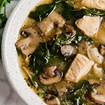 A white soup bowl filled with chicken marsala soup in it.