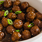 A white bowl filled with Mongolian beef meatballs topped with green onions.
