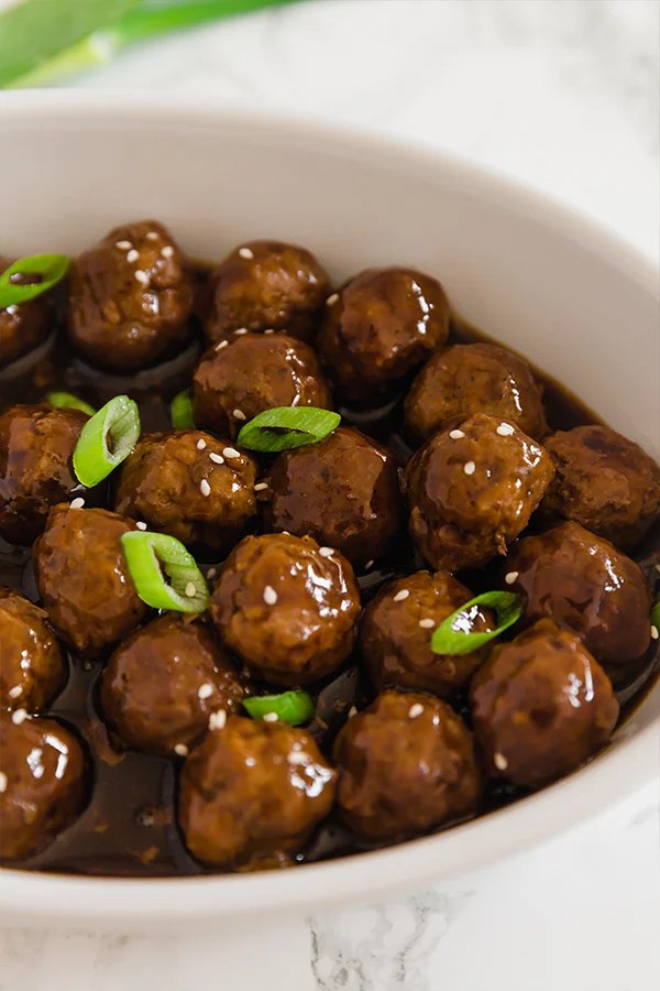 A white bowl filled with Mongolian beef meatballs topped with green onions.