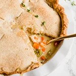 A chicken pot pie with a slice taken out of it and a spoon in it.