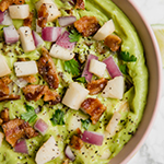 A pink bowl filled with apple bacon guacamole.