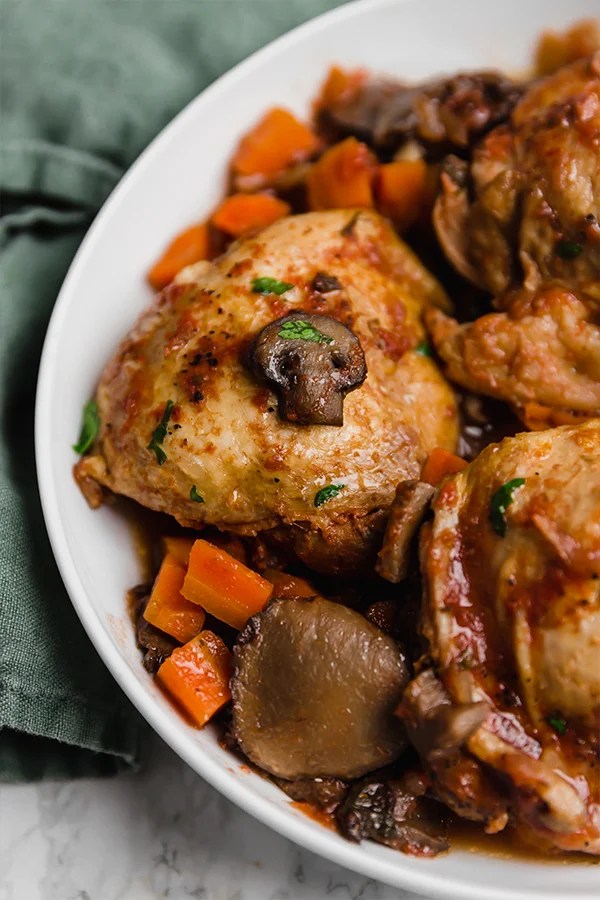 A white serving bowl with slow cooker chicken cacciatore after cooking and ready to be served.