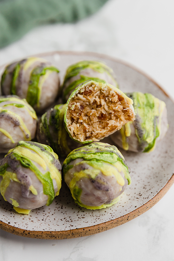 A white plate topped with king cake truffles with a bite taken out of one of them.