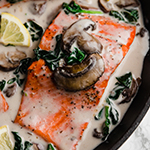 Salmon florentine in a pan topped with mushroom and spinach.