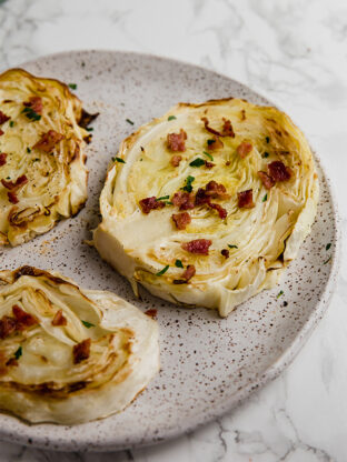 A speckled plate filled with oven roasted cabbage steaks.