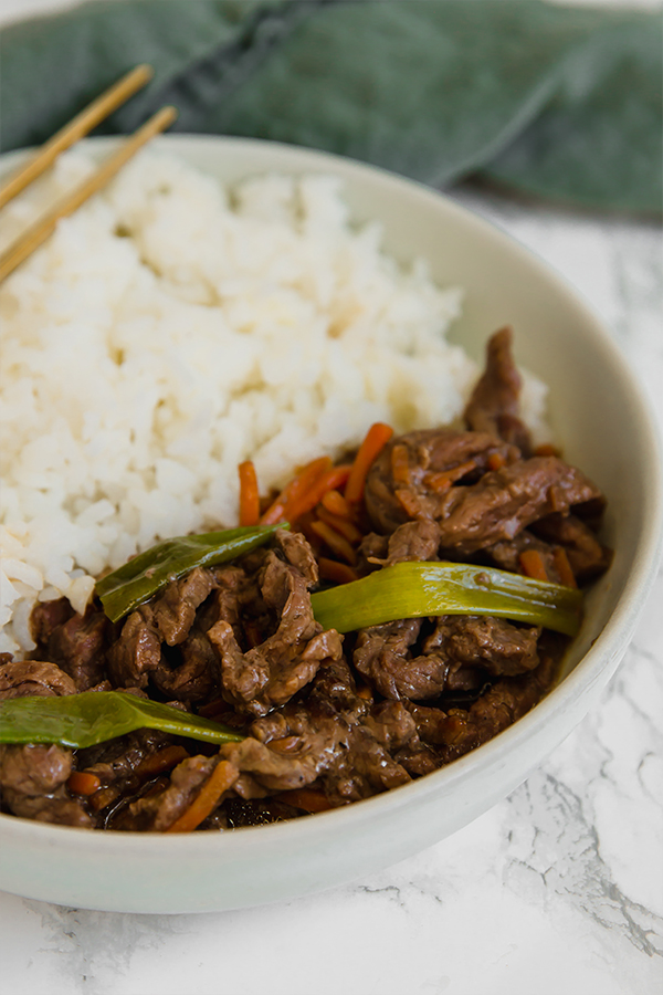 A bowl filled with cauliflower rice and Mongolian beef stir fry.