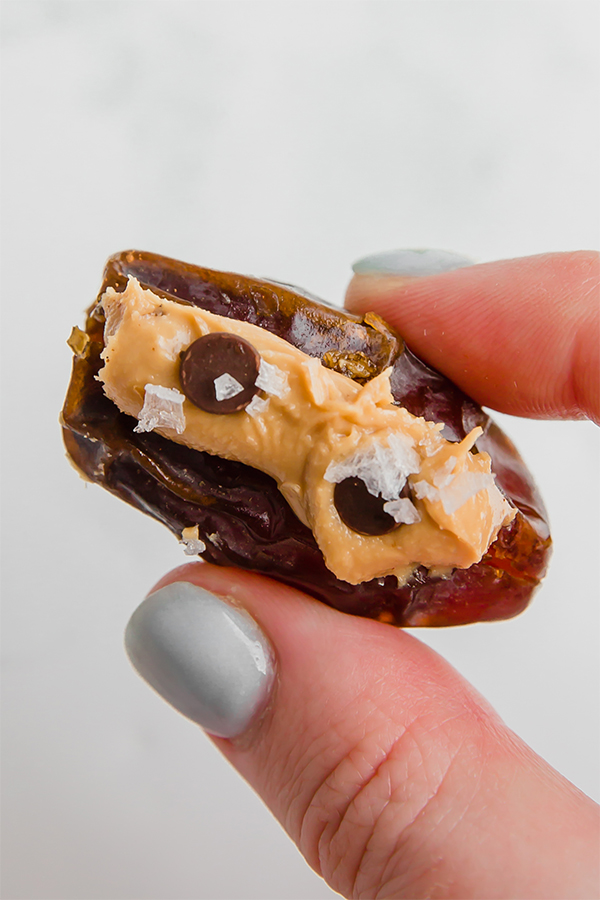 A hand holding an almond butter stuffed date in it.