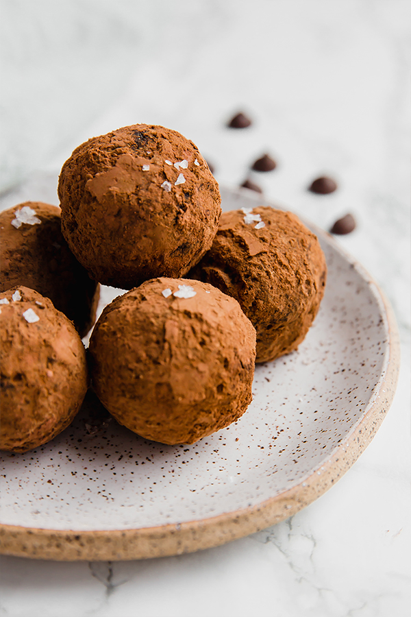 A speckled ceramic plate topped with chocolate avocado protein truffles.