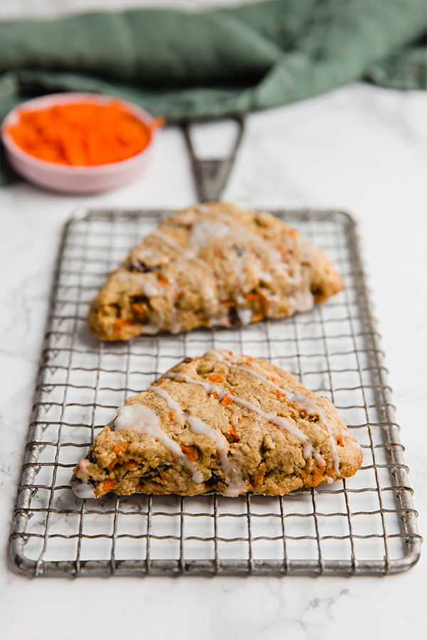 A wire rack with two carrot cake scones cooling on it.