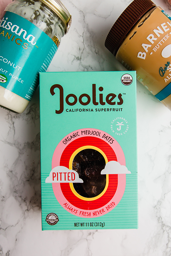 A box of organic dates, coconut butter, and almond butter on a counter.