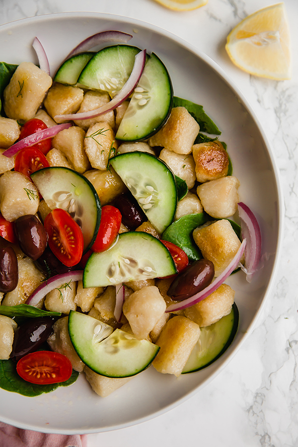 A white bowl filled with Greek gnocchi salad.