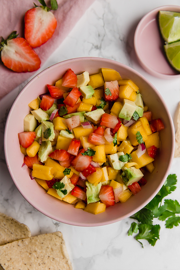 A pink bowl filled with strawberry mango salsa.