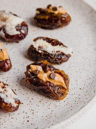 A white plate filled with almond butter and coconut butter stuffed dates.