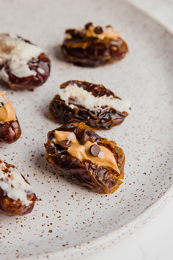 A white plate filled with almond butter and coconut butter stuffed dates.