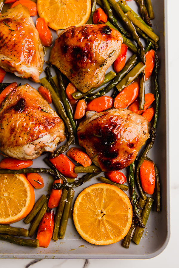 Orange glazed chicken and vegetables on a sheet pan.