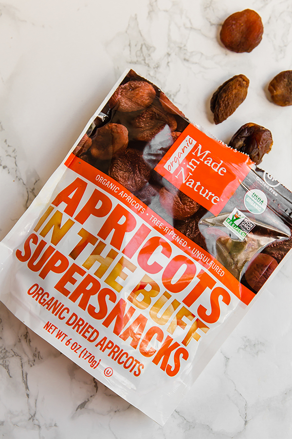 A bag of dried apricots out on a counter with a few apricots spilling out.