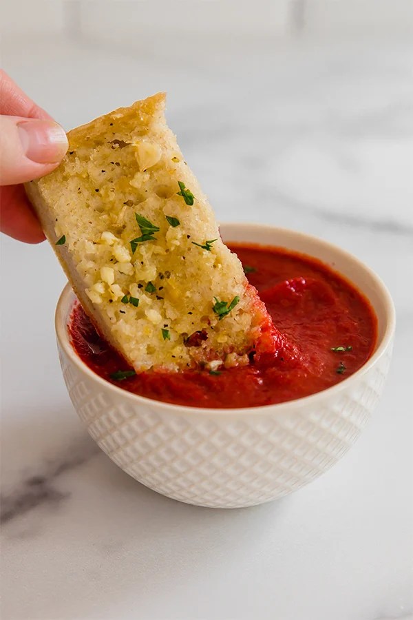 Garlic bread dipping in sauce
