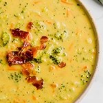 A white bowl filled with broccoli cheese soup.