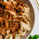 A white bowl filled with slow cooker beef ragu over pasta.