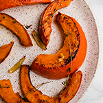 A speckled plate topped with roasted red kuri squash pieces.