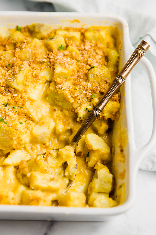 A white baking dish filled with cheesy potato casserole.