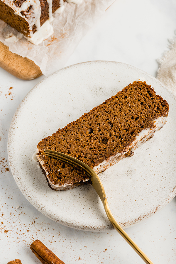 A slice of sweet potato gingerbread on a plate with a fork cutting out a piece.