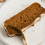 A slice of sweet potato gingerbread on a plate with a fork cutting out a piece.