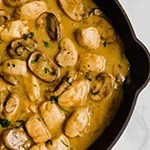 Chicken strogranoff with mushrooms and sauce in a black pan.