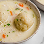 Gluten free chicken and dumplings in a bowl topped with parsley.