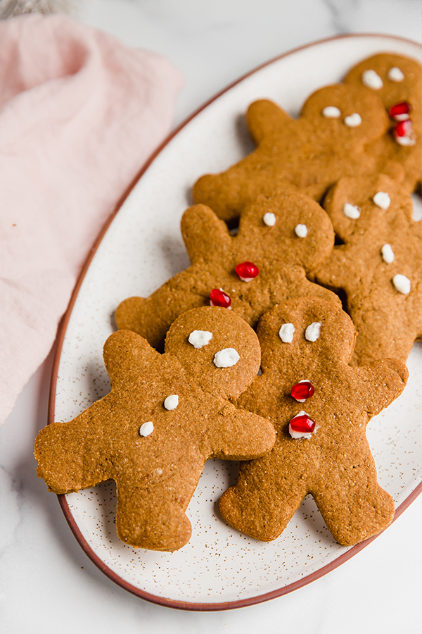 A platter of decorated gingerbread men with pomegranate seeds and frosting.