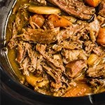 Slow cooker pot roast shredded in a slow cooker with veggies and extra broth.