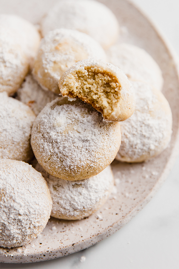 Wedding cookies on a plate with a bite taken out of them