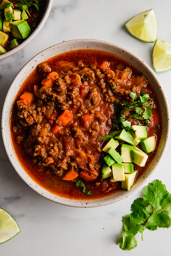 chili in a bowl with avocado and lime