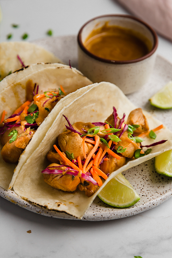 thai chicken tacos on plate with sauce