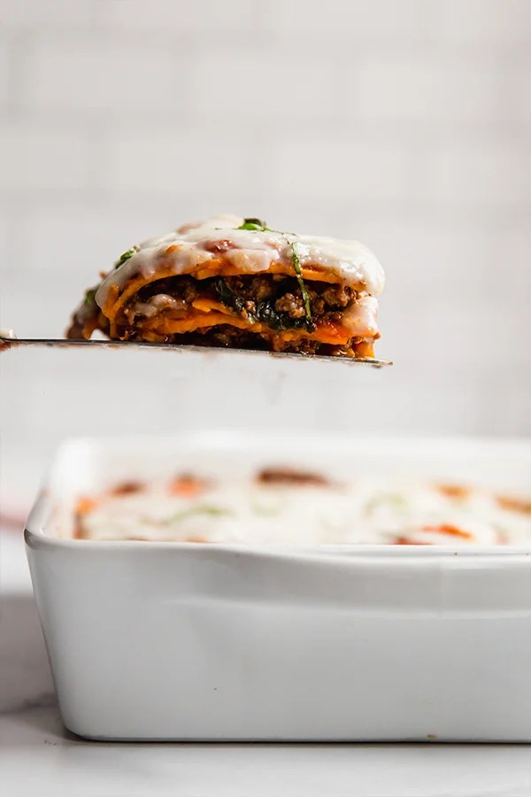 sweet potato lasagna in casserole dish with one slice on spatula